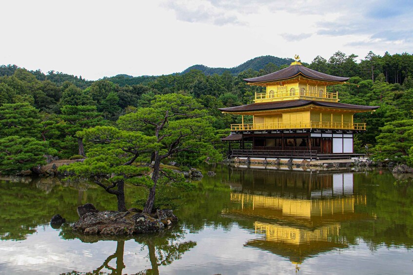 A traditional Japanese temple with a golden roof, surrounded by lush greenery and a calm pond reflecting its structure. 4
