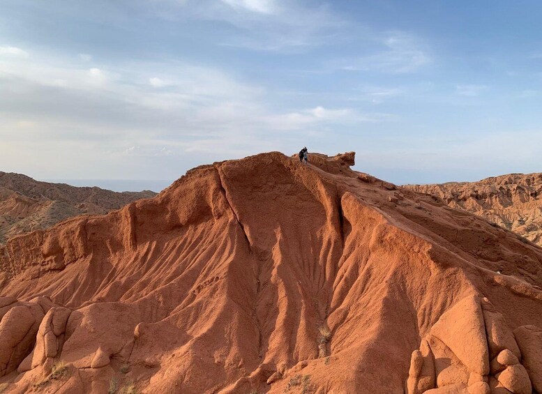 A person hiking on a red rock formation with a clear sky in the background. 5