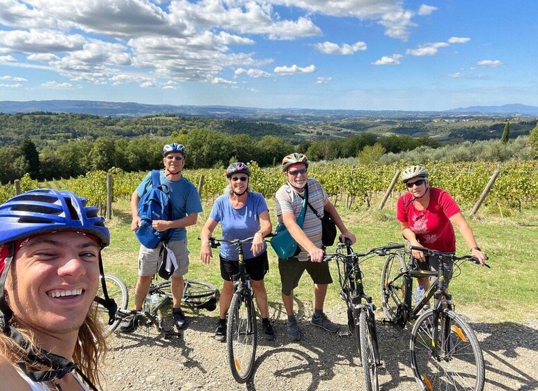 A group of cyclists on a gravel path with vineyards in the background. 1