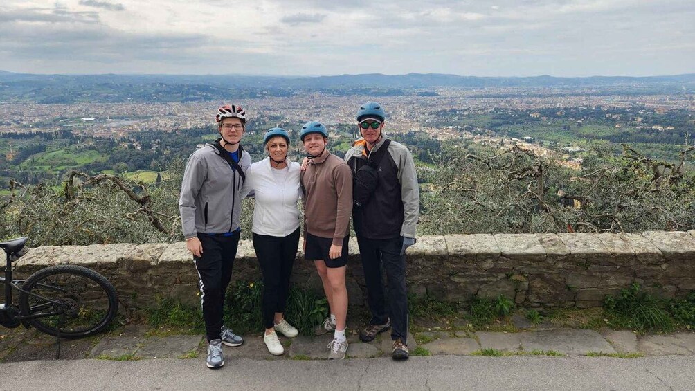 Four people standing on a stone wall with a cityscape in the background. 2