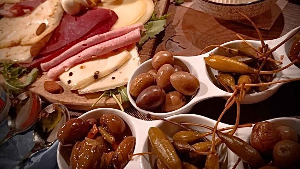 A variety of cheeses, meats, and pickles on a table. 2