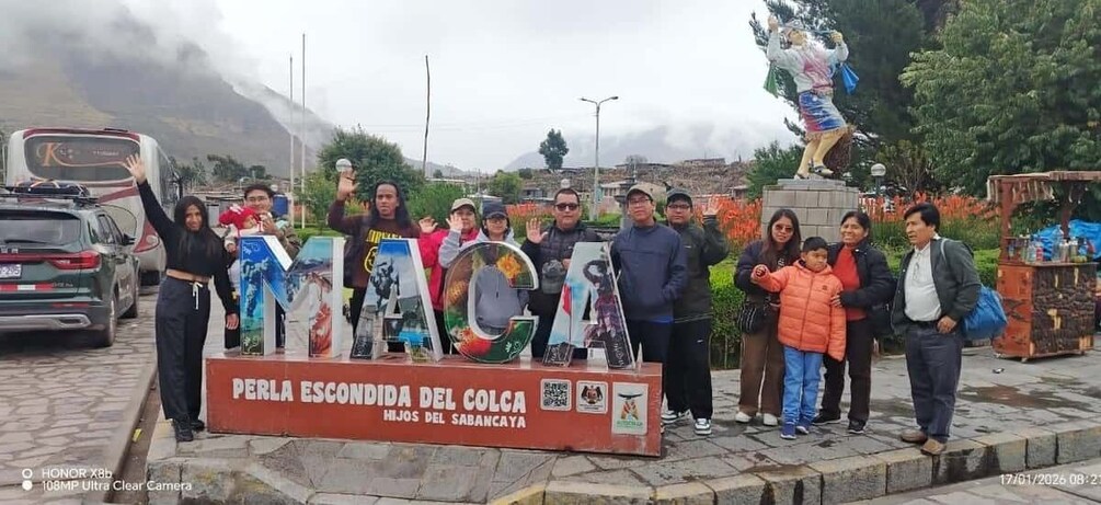 A group of people standing in front of a sign with colorful artwork and a statue in the background. 5