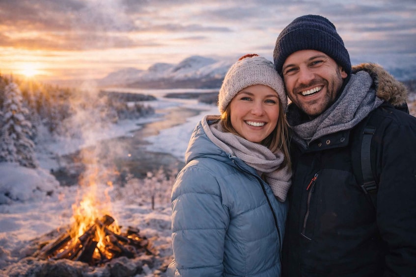 A couple standing by a campfire in a snowy landscape with mountains in the background. 4