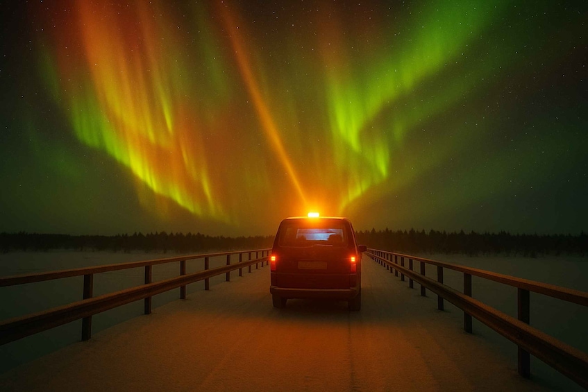A vehicle on a snowy road with aurora borealis in the background. 1
