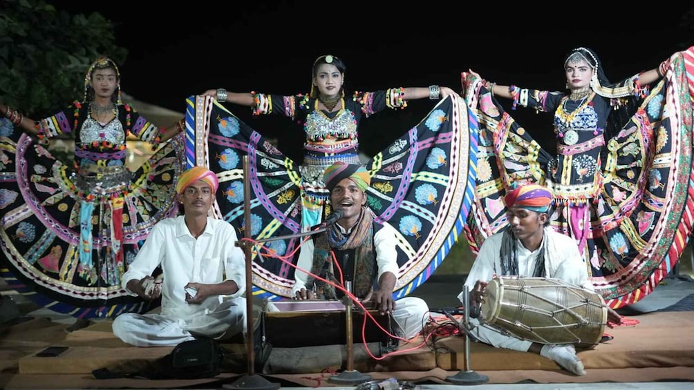 A group of people in traditional attire performing with colorful fabric structures. 4