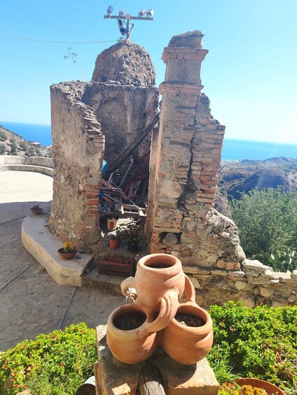 A stone structure with a dome, surrounded by terracotta pots and greenery. 5