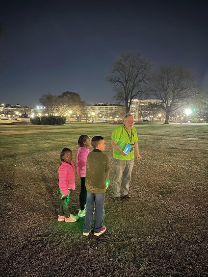 A group of children and an adult in a park at night. 3