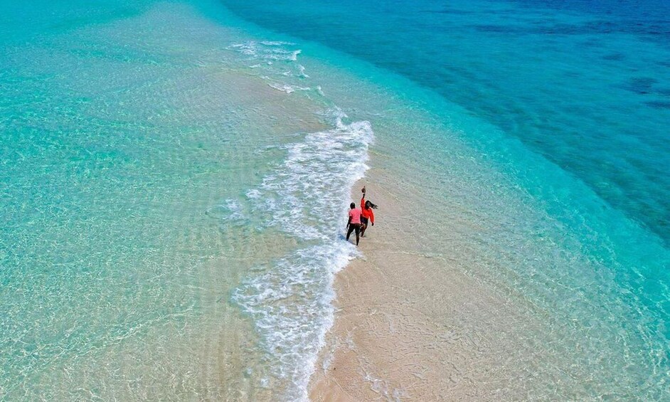 A person walking along a beach with clear turquoise water. 3