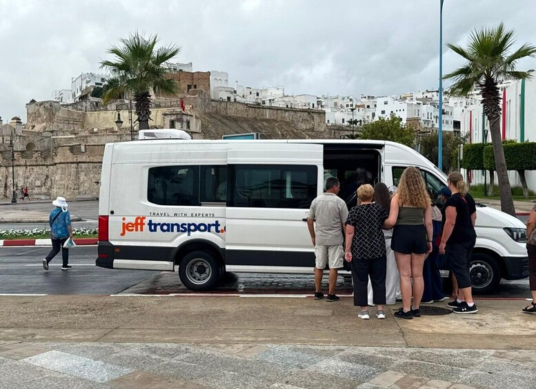 A white van with 'jeff transport' branding parked on a street with people standing beside it. 2