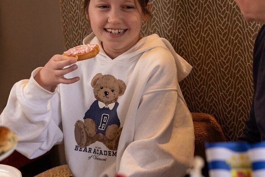 A person wearing a hoodie with a bear graphic and text, holding a donut. 2