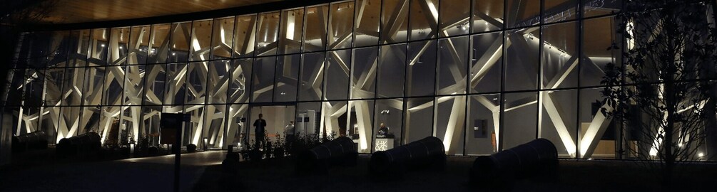 A modern building with a geometric facade and illuminated interior. 1