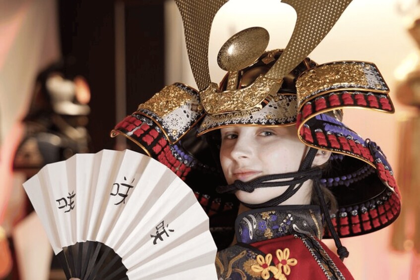 A person in traditional Japanese attire with a fan and a decorative headpiece. 4
