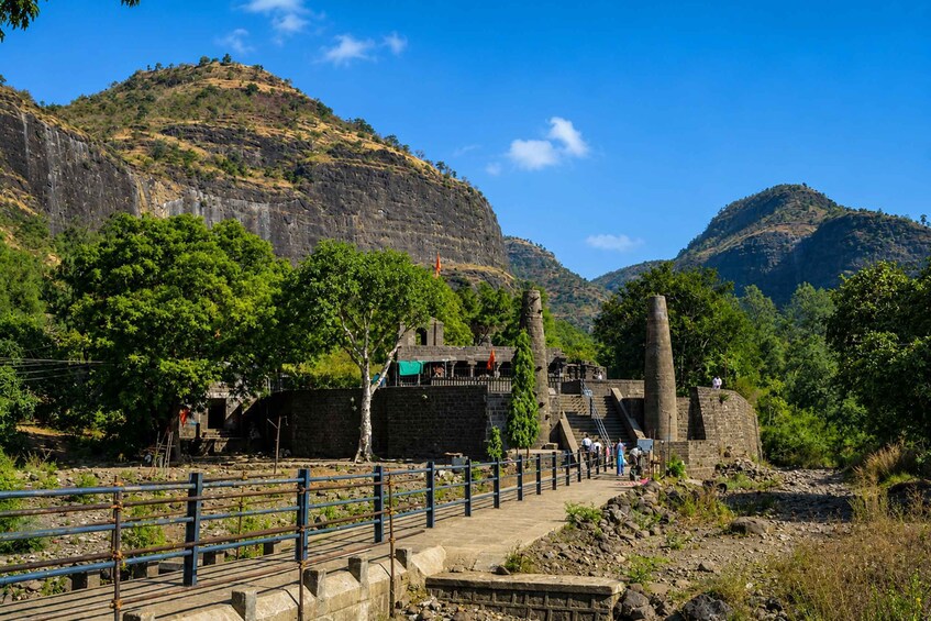 A historical site with ruins, a stone pathway, and a mountainous backdrop. 4