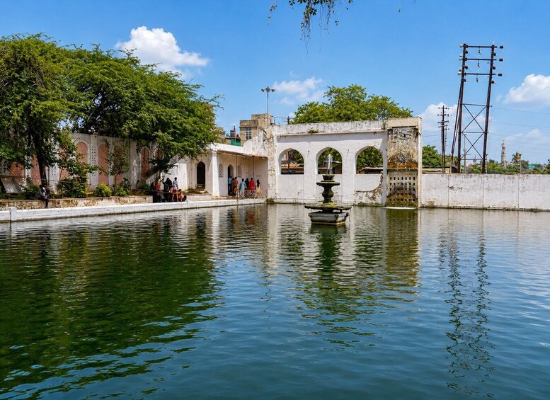 A serene water body with a fountain, surrounded by traditional architecture and greenery. 2