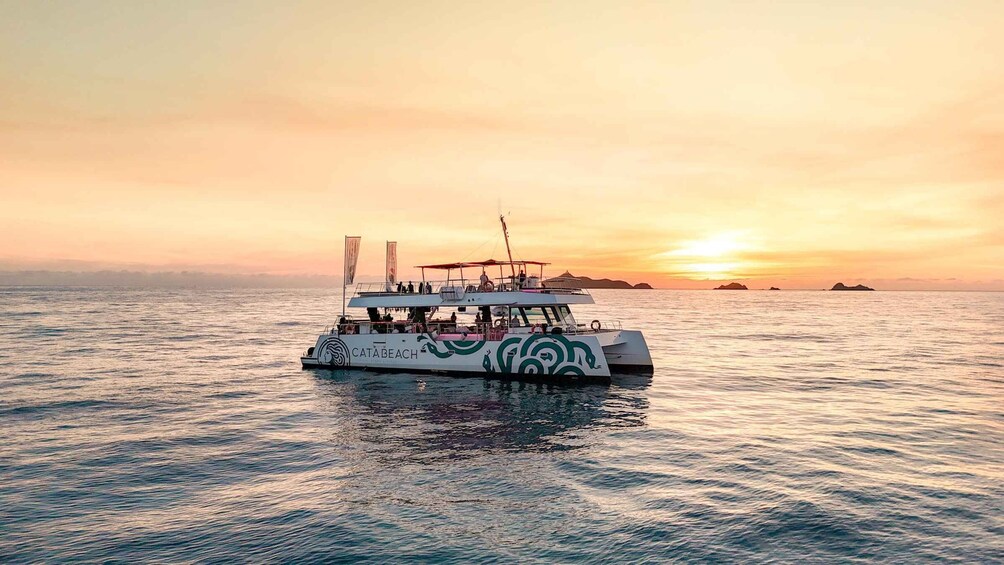 A boat with a green and white design on the water during sunset. 3