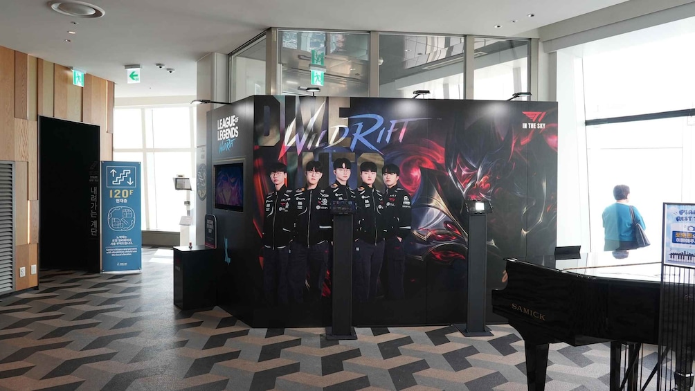 A promotional booth for a gaming event with a large screen displaying team members. 2