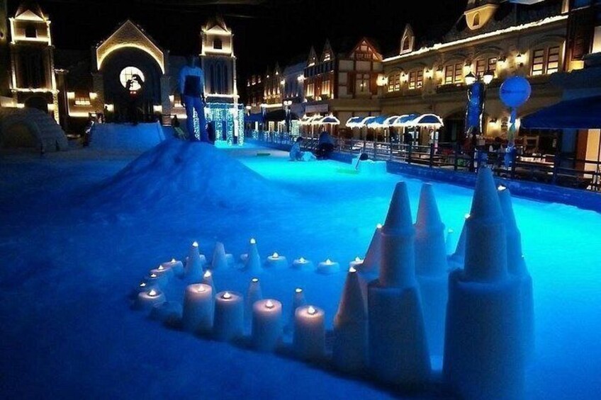 A snow-covered area with illuminated candles and ice sculptures. 2