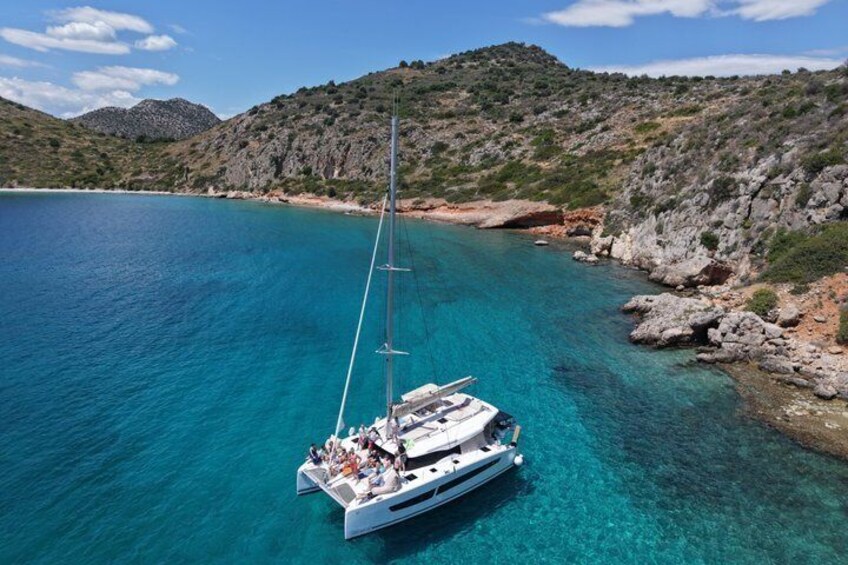 Un velero en un mar turquesa con costas rocosas y colinas al fondo. 1