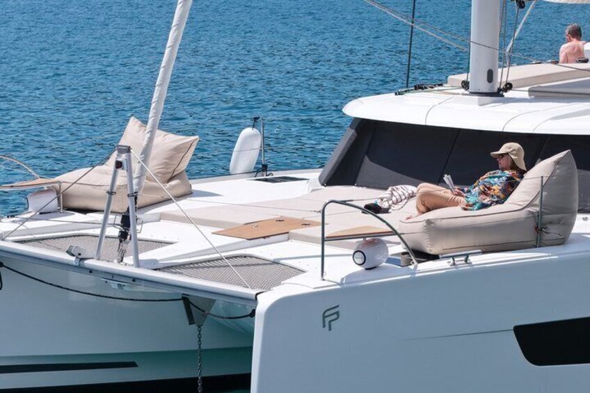 Un yate con una persona descansando en la cubierta, un flotador salvavidas y otra persona al fondo. 3