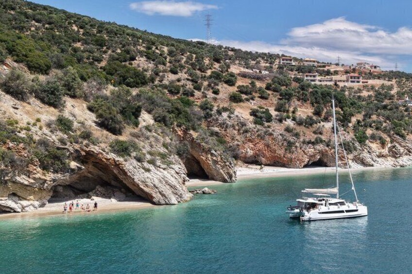 Un paisaje costero con un bote en el agua, acantilados rocosos y una playa con gente. 4