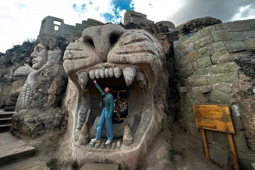 A large stone sculpture of a dragon's head with a person standing in front of it. 2