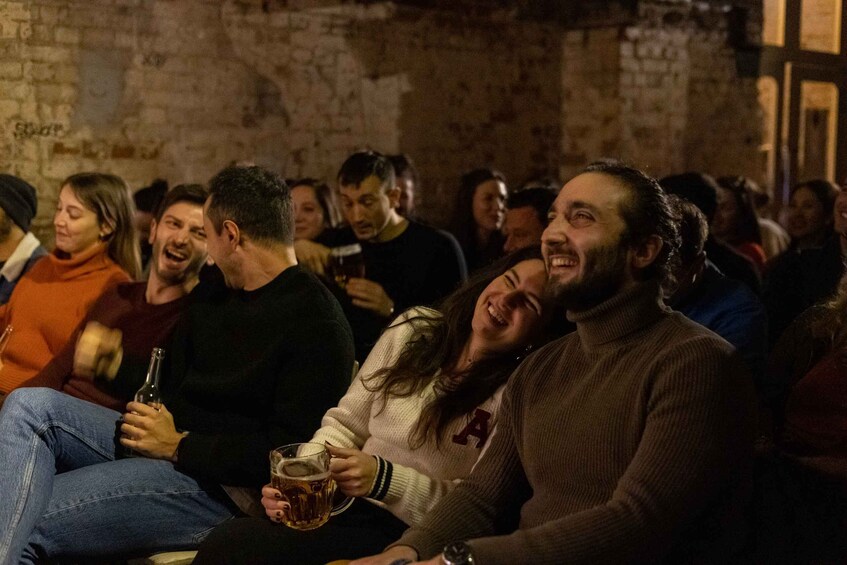 A group of people sitting closely together, some holding drinks. 2
