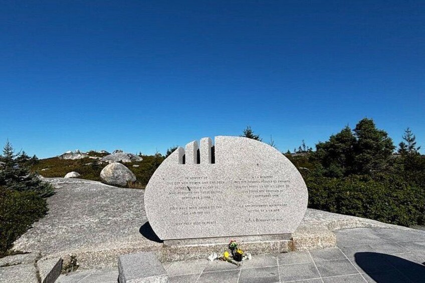 A stone monument with inscriptions, surrounded by a clear sky and a mountainous landscape. 5
