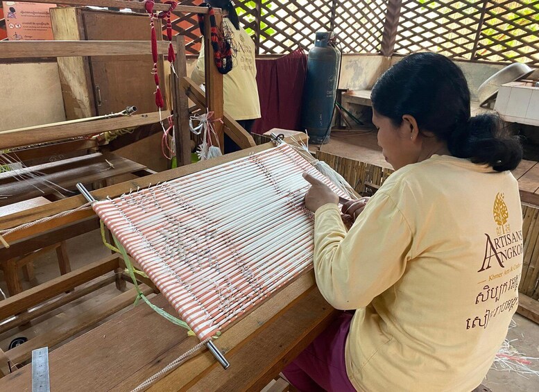 A person weaving on a wooden loom. 4