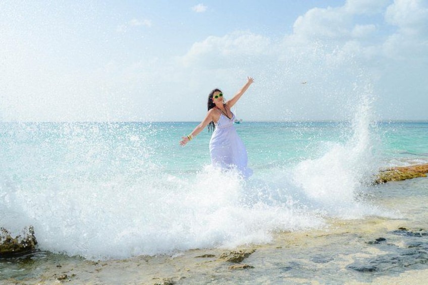 A person in a white dress standing in the ocean with waves crashing around them. 1