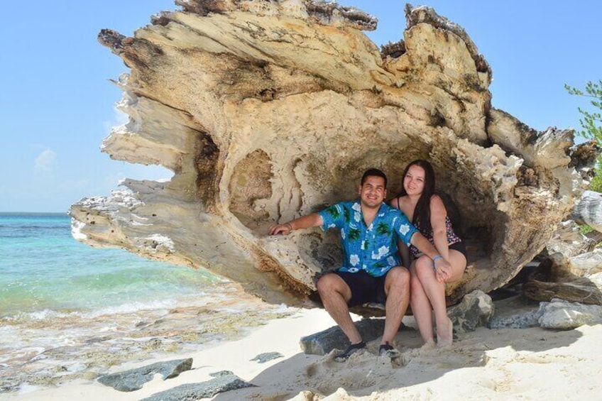 A couple sitting in a natural rock formation by a beach. 5