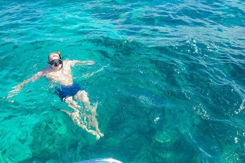 A person swimming in clear blue water. 3