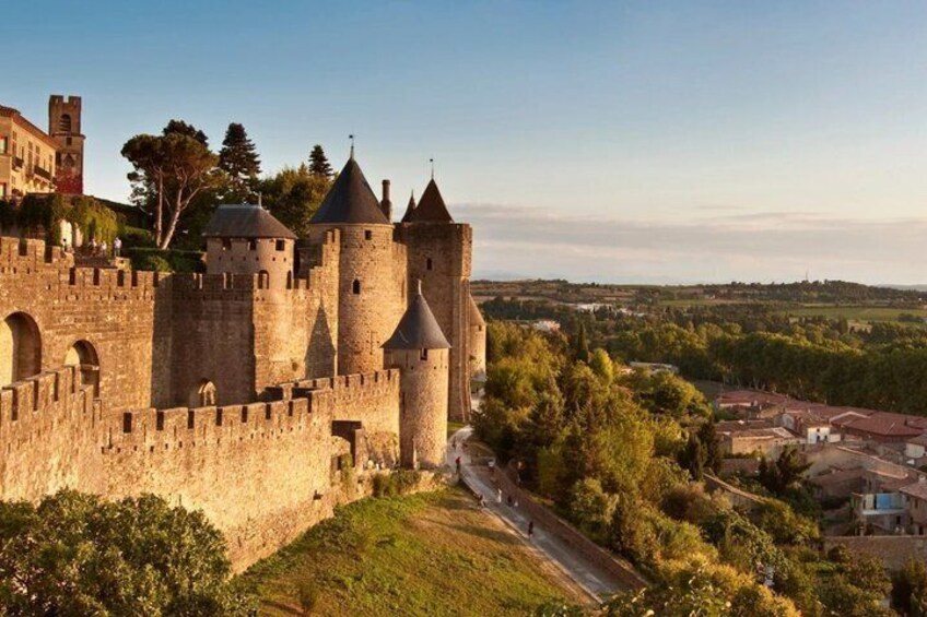 A medieval castle with multiple towers, surrounded by greenery and a small village. 1