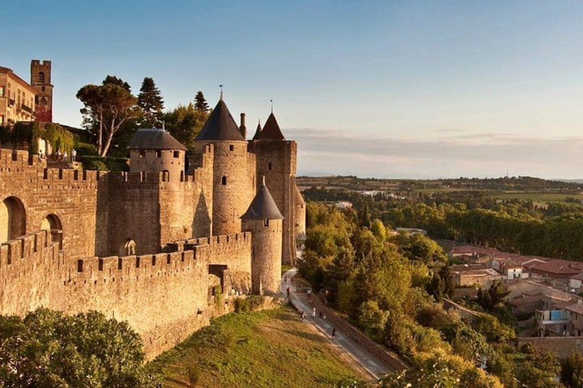 A medieval castle with multiple towers, surrounded by greenery and a small village. 1