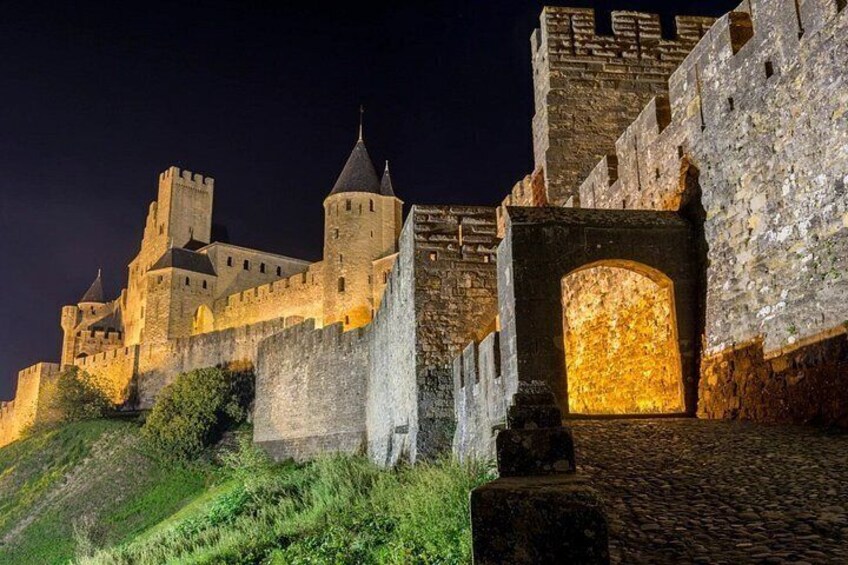 A medieval castle at night with illuminated windows and a stone entrance. 5