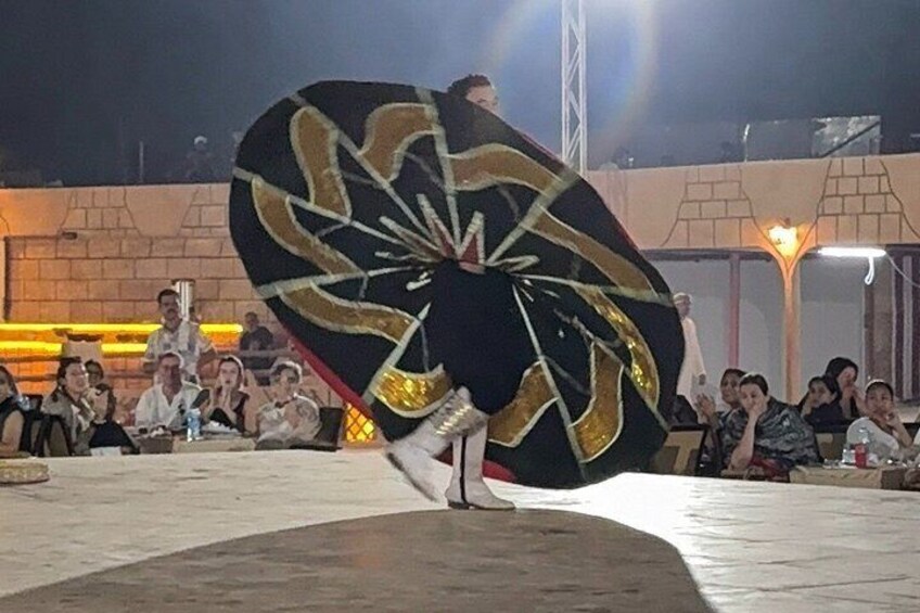 A person performing an umbrella act in an outdoor setting with an audience watching. 2
