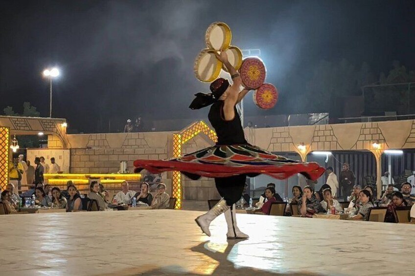 A person performing an acrobatic act with a long ribbon, surrounded by an audience. 3