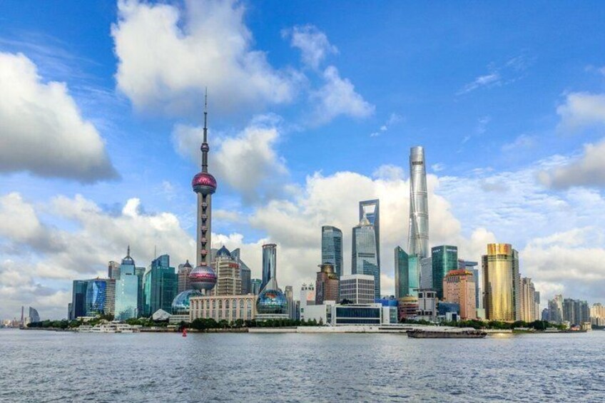A city skyline with modern skyscrapers, a prominent tower, and a body of water in the foreground. 1