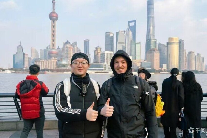 A group of people standing by a waterfront with a city skyline in the background. 2
