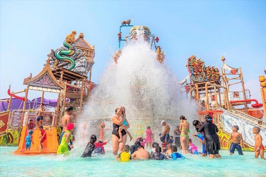 A water park with a large water fountain, slides, and a dragon-themed structure. 1