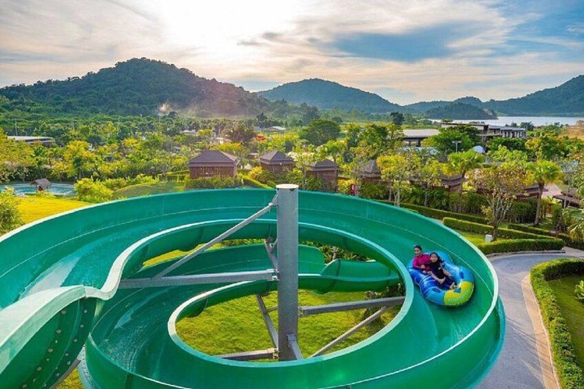 A water slide with a person in a tube, surrounded by greenery and buildings. 3