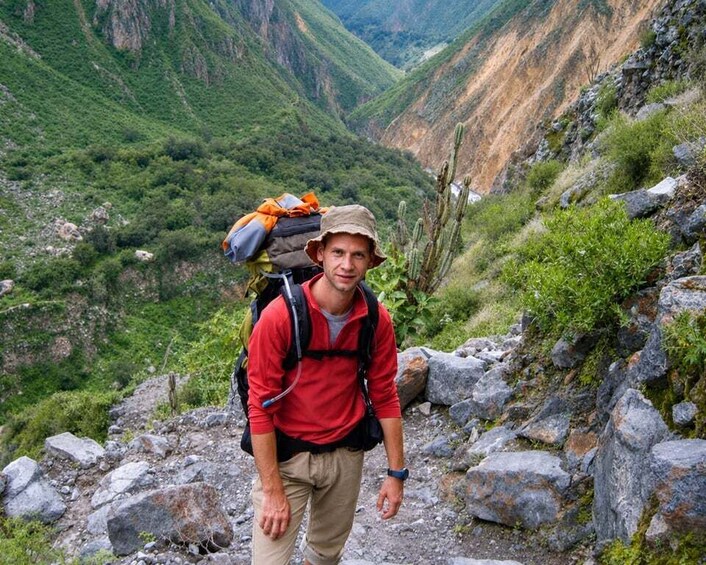 Un excursionista con una mochila en un sendero rocoso en una zona montañosa. 1