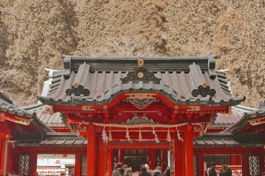 A traditional Japanese temple with red and white architecture, surrounded by a forested area. 1