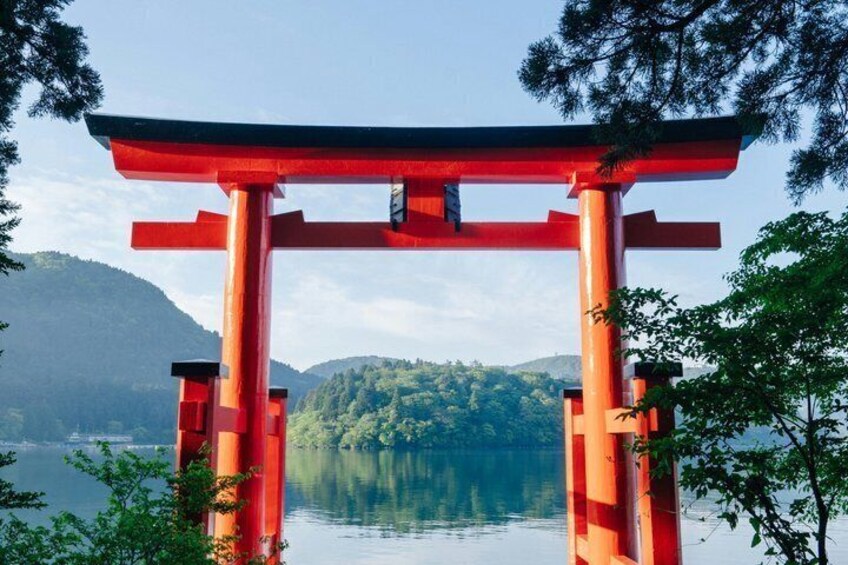 A red torii gate with a lake and forest in the background. 5