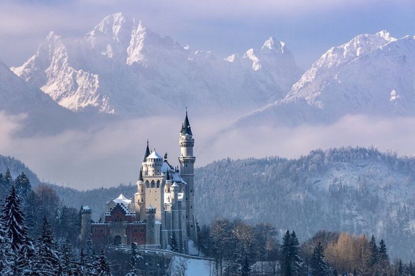 A snow-covered castle with multiple towers, surrounded by a forest and mountains in the background. 3