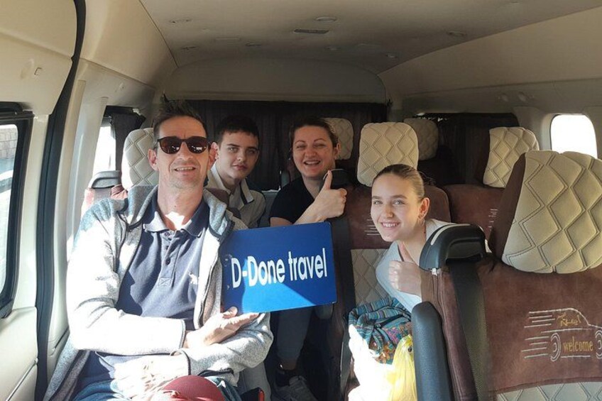 A vehicle interior with passengers holding a sign that reads 'D-Done travel.' 1