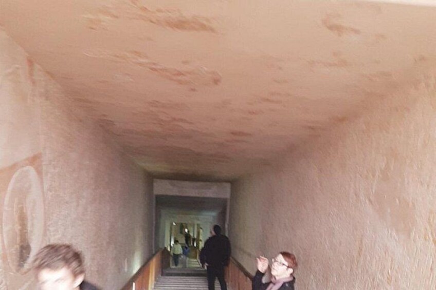 A narrow passageway with a staircase leading to a brighter area. 5