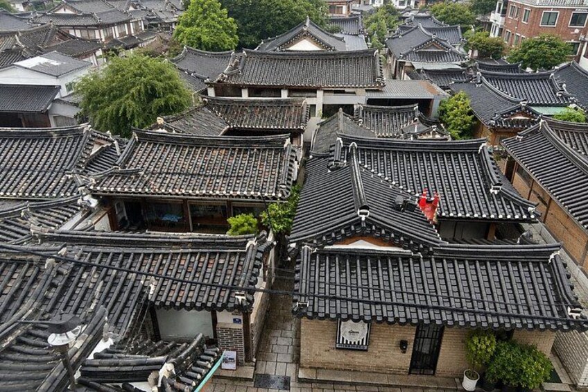A traditional Japanese town with multiple buildings featuring dark tiled roofs and wooden structures. 1