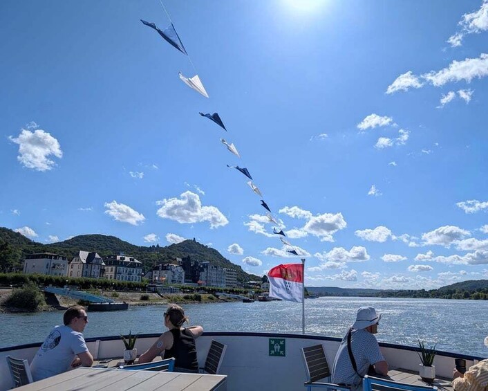 A boat with people on board, a river, and a flag. 3