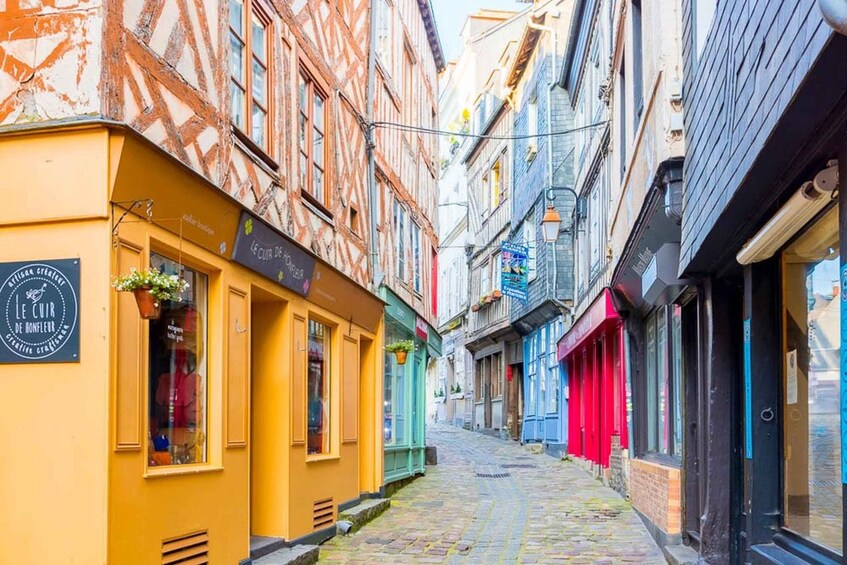 A narrow cobblestone street lined with colorful buildings, some with signs in a foreign language. 3