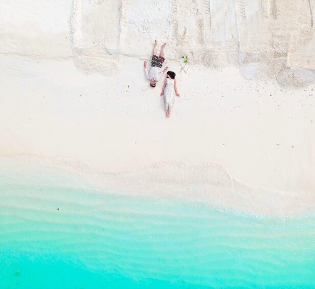 A couple walking on a white sandy beach with clear turquoise water. 5